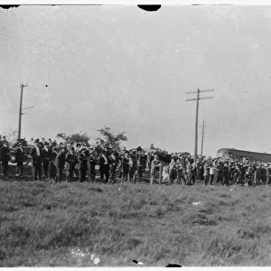 Large crowd of spectators gathered at the edge of a field at
