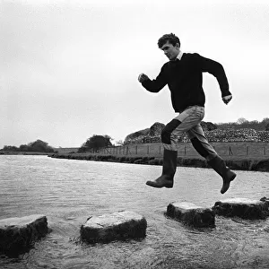 A man leaps along the stepping stones at Ogmore Castle