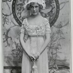 Pauline Chase (1885-1962), American actress, studio portrait in gown and feathered hat. Captioned, Pan Re-Petered'. Chase had recently returned to London from New York, to play Peter Pan at the Duke of York's theatre