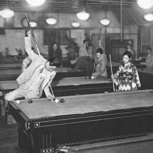 Three young Japanese people play billiards