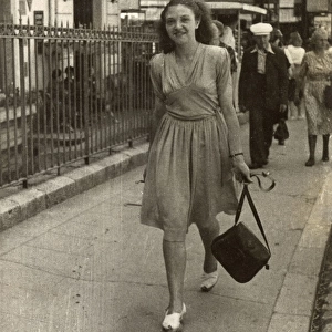 Young lady strolling confidently along, swinging her handbag