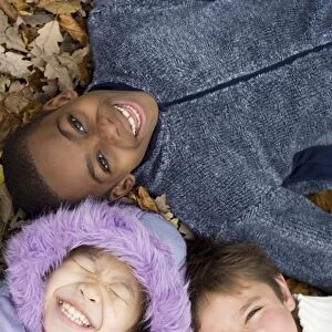 Smiling children lying on autumn leaves