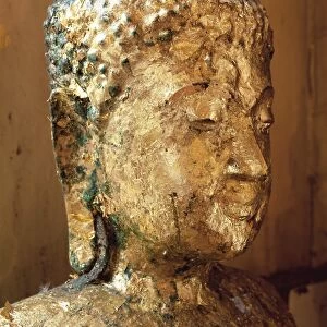 Close-up of the head of a statue of the Buddha covered in gold leaf