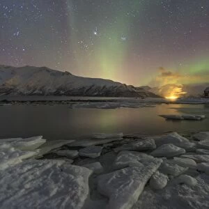 The Northern Lights illuminates the icy landscape in Svensby, Lyngen Alps, Troms