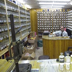 Shop owner surrounded by shelves of hundreds of perfume flasks