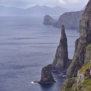 Spectacular 300-400m high cliffs on west coast of Sandoy, Oknadalsdrangur sea stack in foreground