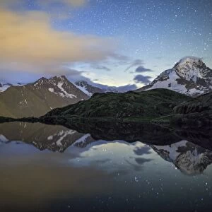 The stars illuminate the snowy peaks and reflected in Lac de Cheserys, Chamonix, Haute Savoie