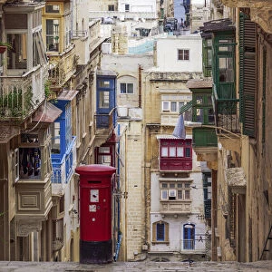 Typical street scene of alley with traditional homes, colorful balconies and red post box, Valletta, Malta, Europe
