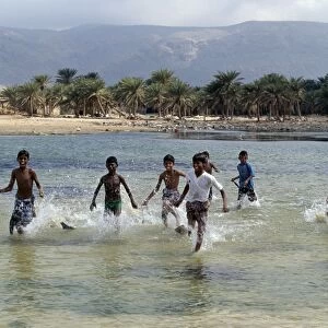 Children enjoy a boat race in a lagoon at Qalansiah