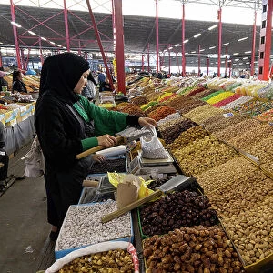 Kyrgyzstan, Bishkek, Osh bazaar, a local woman fills a bag with nuts