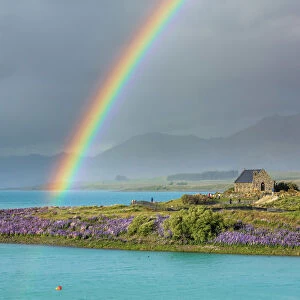 A rainbow over the church of the Good Shepherd and the lupins in bloom by the lake on a