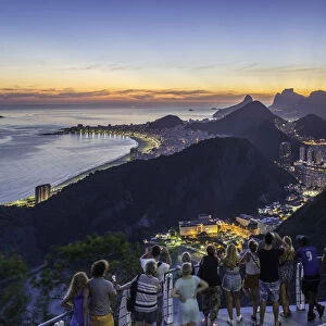 Tourists viewing Christ the Redeemer on Mount Corcovado and the city at sunset