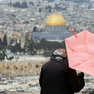 The Dome of the Rock is seen in the background as a tourist holds her umbrella outside