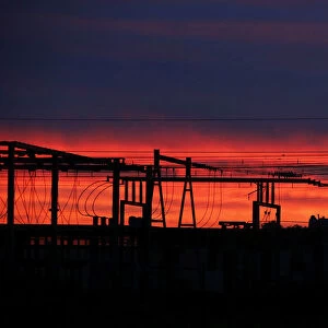 High-tension electrical power pylons are seen in silhouette as the eastern sky brightens