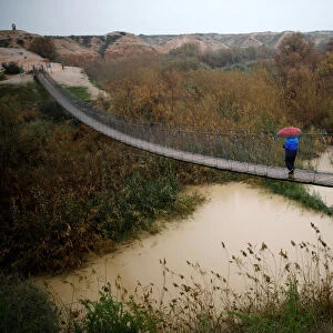A man walks on a bridge crossing over the Besor stream on a rainy day