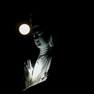 The full moon is seen behind a Buddha statue during the Vesak Day celebrations at Duoc