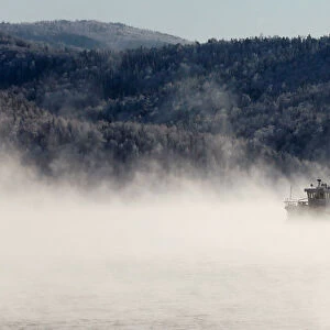 A motorboat travels along the Yenisei River in the Siberian Taiga area as the air