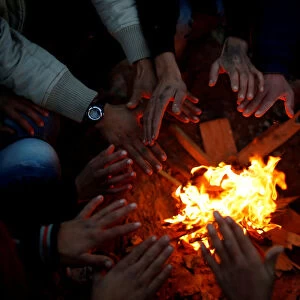 Palestinians warm themselves by a fire, near the border with Israel in the east Gaza