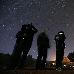 People use night vision goggles to look at the night sky during an UFO tour in the desert