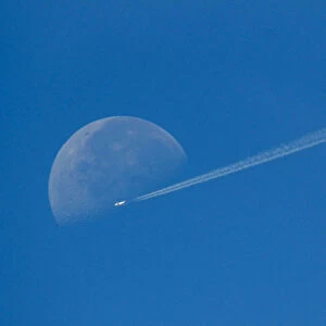 A plane flies in front of the moon