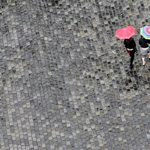Women walk under umbrellas during a rainy day in Prague