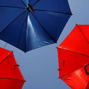 A worker arranges coloured umbrellas hanging over a street in preparation for a music