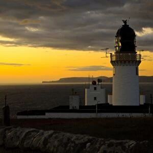 View of clifftop lighthouse at sunset, most northerly point on mainland, with island of Hoy in background