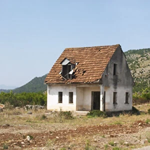 An abandoned house falling to pieces on the dry plain along the road between Shkodra