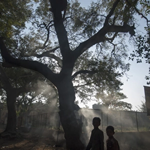 Pedestrians pass burning leaves in Bijapur, Karntaaka, India