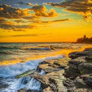 USA, New York, Lake Ontario. Sunset waves on rocky shoreline
