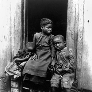 AFRICAN AMERICAN CHILDREN. Three African American children seated in a doorway