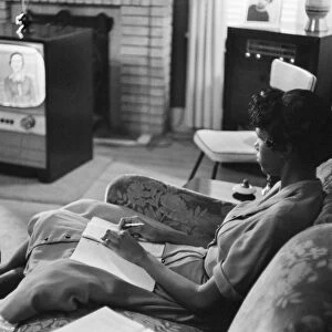 An African American high school girl in Little Rock, Arkansas, learning a lesson from the television at home when the Little Rock schools were closed to avoid integration, September 1958. Photographed by Thomas O Halloran