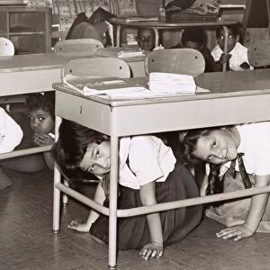 AIR RAID DRILL, 1962. Children under their desks during an air raid drill at P