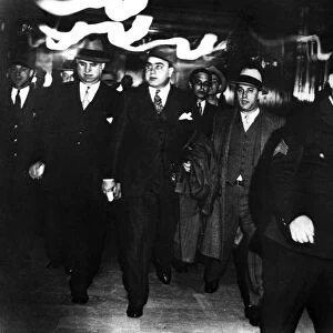 ALPHONSE CAPONE (1899-1947). American gangster. Capone (center) being escorted by federal marshals at the Chicago courthouse after being convicted for tax evasion and sentenced to prison, 1931