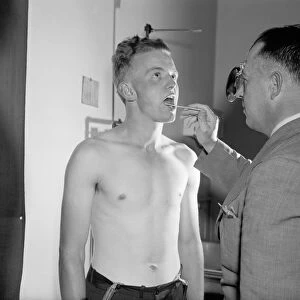 ARMY DOCTOR, c1940. Army recruit Kermit Kuhn being examined by army doctor Major Seth Gayle, Jr