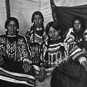 BLACKFOOT WOMEN, c1907. Five Blackfoot women wearing clothing decorated with beads and cowrie shells. Photograph by Norman Fosyth, c1907