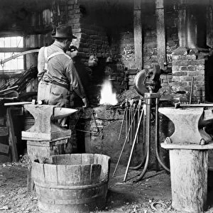 BLACKSMITH, c1906. An American blacksmith at work in his shop. Photograph, c1906