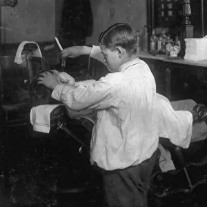 BOY BARBER, 1917. Frank de Natale, a 12-year old barber, lathers and shaves customers
