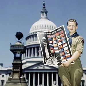 BOY SCOUTS, 1943. A Boy Scout holding a poster for the United Nations Fight for