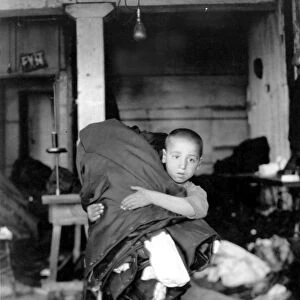 CHILD LABOR, 1910. A New York City tenement boy with a bundle of garment work to be done at home