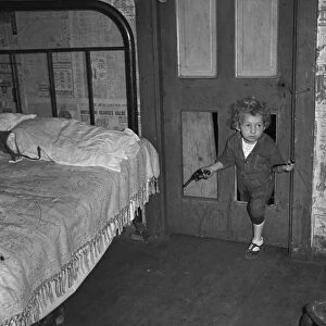 COAL MINERs CHILD, 1938. Coal miners child using a hole in the door to enter