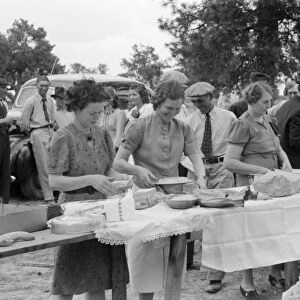 COMMUNITY DINNER, 1940. Women setting out dinner at the all day community sing in Pie Town