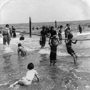 CONEY ISLAND: BEACH, c1897. Children holding onto ropes and playing in the surf at Coney Island