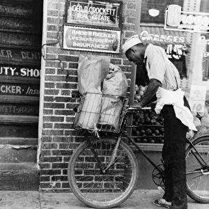 DELIVERY BOY, 1938. An African American boy delivering groceries with a bicycle in Caruthersville