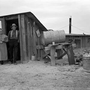 DUGOUT HOME, 1939. A farm couple from drought stricken Oklahoma standing in the