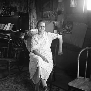 DUGOUT INTERIOR, 1939. A farm wife seated in a one-room basement dugout in Dead Ox Flat
