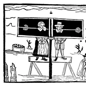 ENGLISH PILLORY. A man and a woman standing in a pillory while villagers stand and jeer