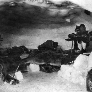 ESKIMO IGLOO. The interior of an Eskimo igloo with a man and his dog inside. Photograph