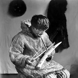 ESKIMO IVORY CARVER, c1912. A seated Eskimo man working as an ivory carver, Arctic region