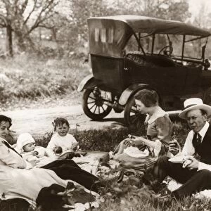 A family having a picnic on the side of a road, with a Model T Ford in the background. Photograph, c1918